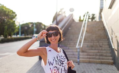 Güzel esmer, güneşli şehir caddesinde alışveriş yapan, şehir tarzı, gülümseyen, yaz trendi.