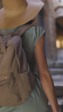 Dikey çekim. Elbise giymiş güzel bir kız Eski Şehir 'in dar sokaklarında yürüyor. Sırt çantalı bir turist. Yaz seyahati