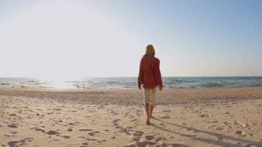 Genç bir kadın sahilde romantik tatilin tadını çıkarıyor. Gün batımının ve okyanus dalgalarının tadını çıkarıyor. Kahkaha ve mutluluk. Şık kız eğleniyor