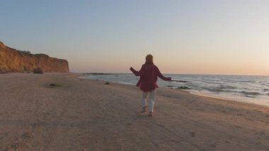 Genç bir kadın sahilde koşuyor ve tatilin tadını çıkarıyor. Kahkaha ve mutluluk. Şık kız eğleniyor