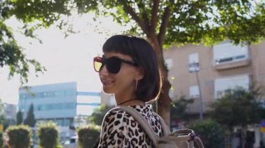 Güneşli şehir caddesinde yürüyen güzel esmer kadın. şehir tarzı, gülümseme, yaz trendi.