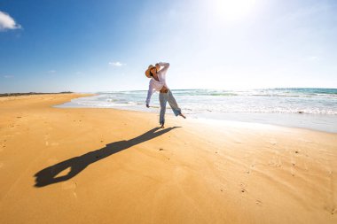 Sahilde kameraya bakan güzel bir kadının portresi. Bir kadın sahilde duruyor, sahil melteminin tadını çıkarıyor. Bir kız deniz kenarında bir anın tadını çıkarır. Romantik ruh hali.