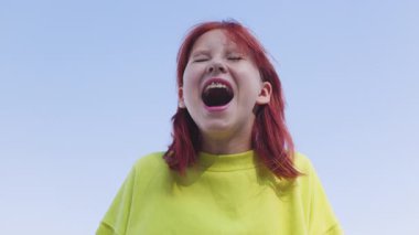 Duygusal bir genç kız kameraya bakar, çığlık atar ve negatif duygularını bağırarak ifade eder. Gençler bağırıyor. Yavaş