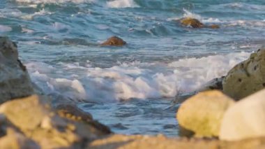 Hayfa gezinti güvertesi. Gün batımında deniz. Deniz dalgaları kayalık kayalıklara çarpar ve her yerde köpük ve sprey oluşturur. İsrail