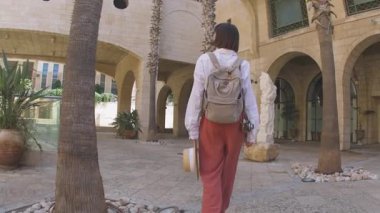 Sırt çantalı bir kadın turist şehrin eski turistik bölgesinde boş bir caddede yürüyor ve Jaffa 'daki tatilinin tadını çıkarıyor.