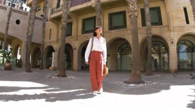 Sırt çantalı bir kadın turist şehrin eski turistik bölgesinde boş bir caddede yürüyor ve Jaffa 'daki tatilinin tadını çıkarıyor.
