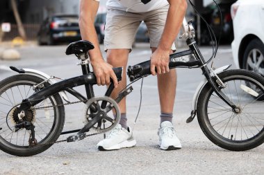 Bisikletli bir adam bir kazadan sonra sokakta ikiye bölünmüş bir çerçeveyle duruyor.