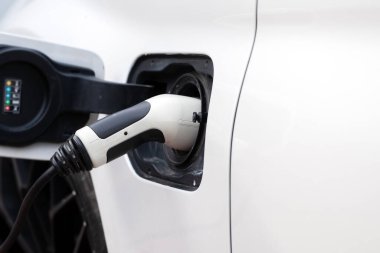Elektrik kablosu elektrikli aracın şarj cihazına bağlı. Otoparkta elektrikli araba şarj etmek.