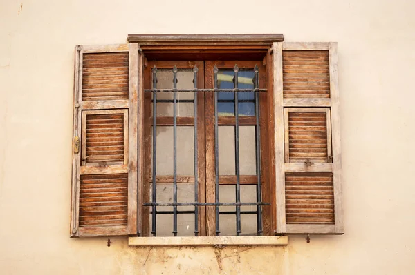 Vintage opened brown wooden shutters on a window of a house