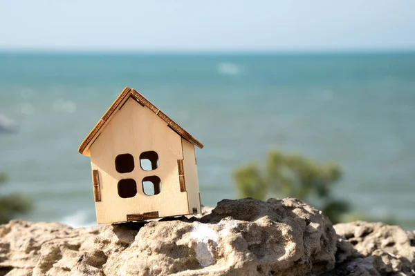 夏日晴空万里 岩石上的小玩具屋 背景是蓝色的大海 — 图库照片