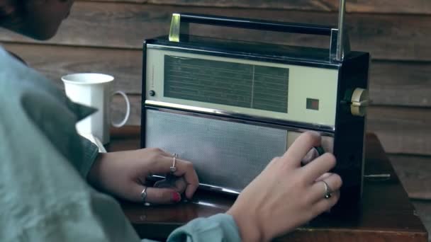 女孩在老式无线电接收机上搜寻电台频率或电波 她转动调谐旋钮 箭头在天平上移动 1970年代的复古接收机 — 图库视频影像