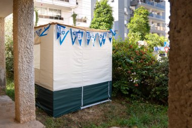 Yahudi bayramı boyunca İsrail 'de bir yerleşim yerinin bahçesindeki beyaz paçavra sukkah.
