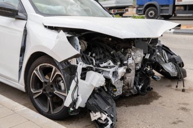 Beyaz yolcu vagonu bir kazada kaza yaptı. Motor dışarıda asfalta düştü. Arabanın altına sıvı dökülmüş.