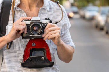 Şehirli kadınların elinde deri çantalı Retro film kamerası. Kadın fotoğrafçı yaz günü sokakta fotoğraf çekiyor..