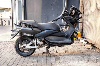 Ön tekeri olmayan kırık bir motosiklet dışarıda duruyor.