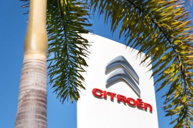 Rishon Lezion, İsrail - 3 Nisan 2024. Palmiye ağaçlı beyaz bir tabela üzerinde Citroen logo araba şeridi. İsrail ve diğer tropikal ülkelerde Citroen araç satışları