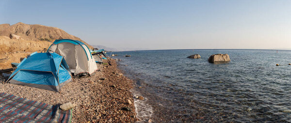 Панорамный вид палаточного лагеря на берегу Красного моря ранним утром в Эйлате, Израиль. Восход солнца на Красном море.