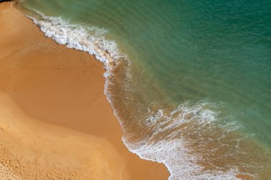Sahilde dalgalar, güneşli bir günde kıyıda soyut çizgiler.