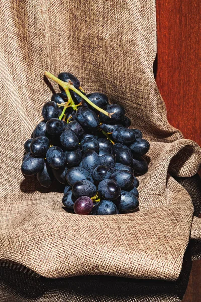 Вертикальное Изображение Кучи Темного Винограда Вретище Над Черной Отражающей Поверхностью — стоковое фото