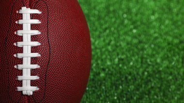 Kahverengi bir Amerikan futbol topunu yeşil çimlerin üzerine yakın çekim.