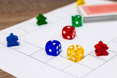 Izgara oyun alanı üzerinde renkli parçalar ve zarlar bulunan bir masa oyununun yakın plan görüntüsü.