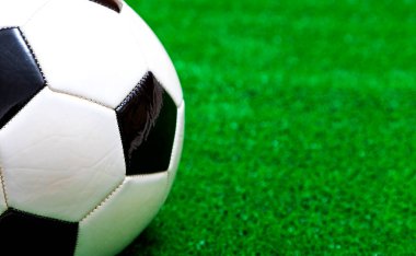 Yapay yeşil çimenler üzerinde klasik siyah-beyaz futbol topunun yakın çekimi.