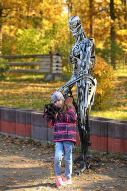 Bucha, Ukrayna - 16 Ekim 2022: Şehir peyzaj parkında demir bir adamın heykelinin yanında poz veren kız.