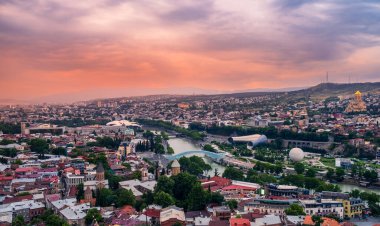 Old Tbilisi cityscape with Mtkvari or Kura river, Cathedral, bridge of peace, Rike park and presidential palace at sunset with dramatic sky. Tiflis is popular tourist destination in Georgia.