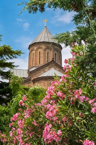 Domes of Metekhi church in flowers in old town of Tbilisi, Georgia. Virgin Mary Assumption Church of Metekhi is Georgian Orthodox Christian church, famous tourist attraction. Vertical orientation.