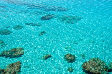 Kıbrıs 'ta Ayia Napa yakınlarında kristal berrak deniz suyu. Kayalar ve kum, dalgalar ve dalgalarla turkuaz sularda görülür. Deniz yüzeyinin yaz arkaplan resmi.