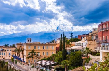 Taormina, Sicilya, İtalya. Tepe ve Etna 'daki Taormina kasabasının panoramik manzarası mavi gökyüzündeki bulutların arasında volkan oluşturur. Popüler turizm merkezi.