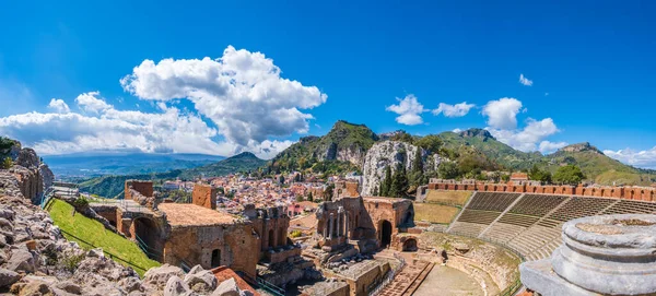 stock image Taormina on Sicily, Italy. Ruins of ancient Greek theater, mount Etna covered with clouds. Taormina old town and mountains in background. Popular touristic destination on Sicily.