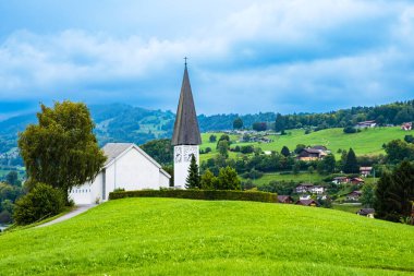 İsviçre 'nin Bern kantonu Bernese Oberland bölgesinde Thun Gölü kıyısındaki Spiez kasabası yakınlarındaki tepelerde beyaz kilisesi ve tipik İsviçre evleriyle Faulensee köyü.