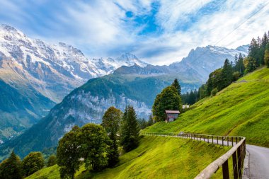 Lauterbrunnen Vadisi, İsviçre 'nin göz kamaştırıcı dağ manzarası. Murren 'dan Gimmelwald köyüne yürüyüş yolu. İsviçre Alplerinde Jungfrau dağ sıraları, yeşil çimenler ve ahşap evler karla kaplandı.