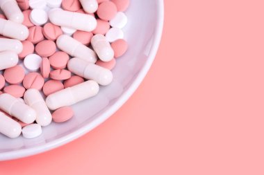 Pembe arka plan, pembe, beyaz haplar ve kapsüllerle dolu. Tıbbi tedavi, hormonal doğum kontrol hapı ya da zayıflama haplı diyet. Metin için alanı kopyala.