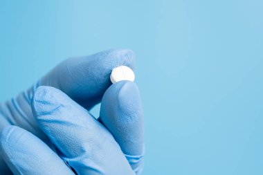 Doktor, eczacı ya da bilim adamı beyaz hap, vitamin ya da mavi arka planda takviye tutuyor. Tıp ya da ilaç tedavisi, bilimsel araştırma. Yaklaş, seçici odaklanma.