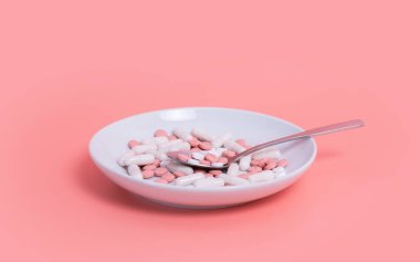 Beyaz ve pembe zayıflama hapları ve kapsüller pembe arka planda kaşıkla beyaz tabakta. Tıbbi tedavi, kadın uyuşturucu bağımlılığı veya diyet konsepti.