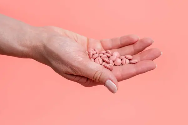White and pink pills, stethoscope and heart on white plate. Concept of cardiac diet and cardiology treatment of cardiovascular diseases with medication, dietary supplements and vitamins. Heart health.