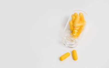 Sarı haplar ve yalancı cam şişeler beyaz arka planda izole edilmiş. Tıbbi tedavi kavramı ilaç, vitamin ya da kapsüllerdeki takviyeler, sağlık hizmetleri ya da uyuşturucu bağımlılığı. Boşluğu kopyala.