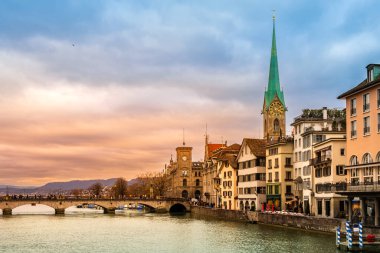 Zürih şehir merkezi, İsviçre. Zuerich 'in ünlü Fraumunster ve Munsterbrucke köprüsüne sahip eski bir kasabası. Gün batımında Limmat nehrinin kıyısında. Kışın dramatik bir gökyüzü var..