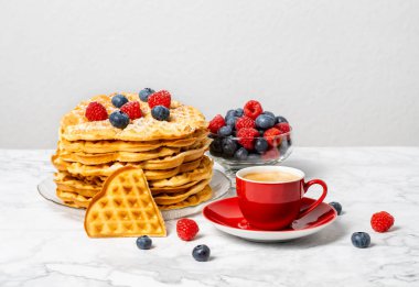 Bir yığın Belçika waffle 'ı, böğürtlen, bal ve kırmızı kahve: mermer masada nefis bir yaz kahvaltısı. Kalp şeklinde waffle ve ahududu ve yabanmersini karışımı..