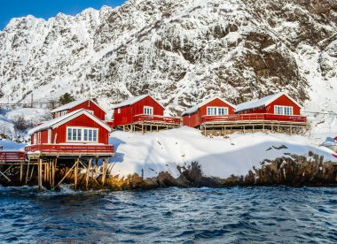 Lofoten Köyü 'nde, Lofoten Adaları' nda, su tesislerinde bulunan geleneksel kırmızı ahşap balıkçı kulübeleri var. Kuzey Norveç 'teki Karlı İskandinav manzarası.