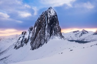 Norveç 'in Senja Adası' ndaki Fjordgard yakınlarındaki Hesten patikasından görülen Segla dağı zirvesi. Karlı dağların olduğu manzaralı kış manzarası ve gün batımında soğuk fiyort suyu..