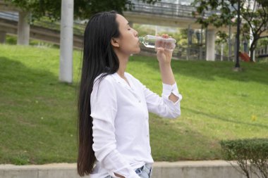  Güzel Latin kadın şişeden su içiyor..