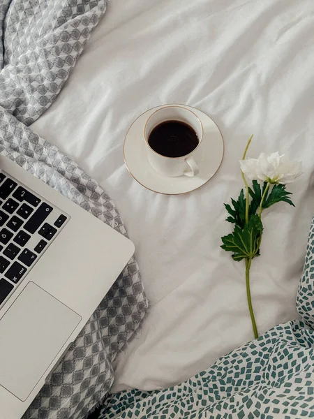 cup of coffee on bed with macbook