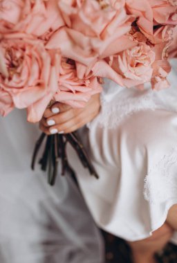 Gelinlikli gelin elinde güzel bir buket tutuyor.