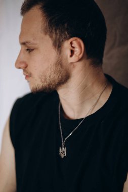 a man in a T-shirt with a beard and a chain coat of arms of Ukraine
