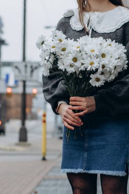 Elinde bir buket gül tutan genç bir kadın.