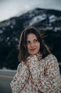 Dağlarda bir kayanın üzerinde oturan kışın giydiği beyaz bir kadın.