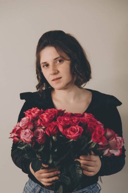 Elinde bir buket gülle esmer bir kızın fotoğrafı.